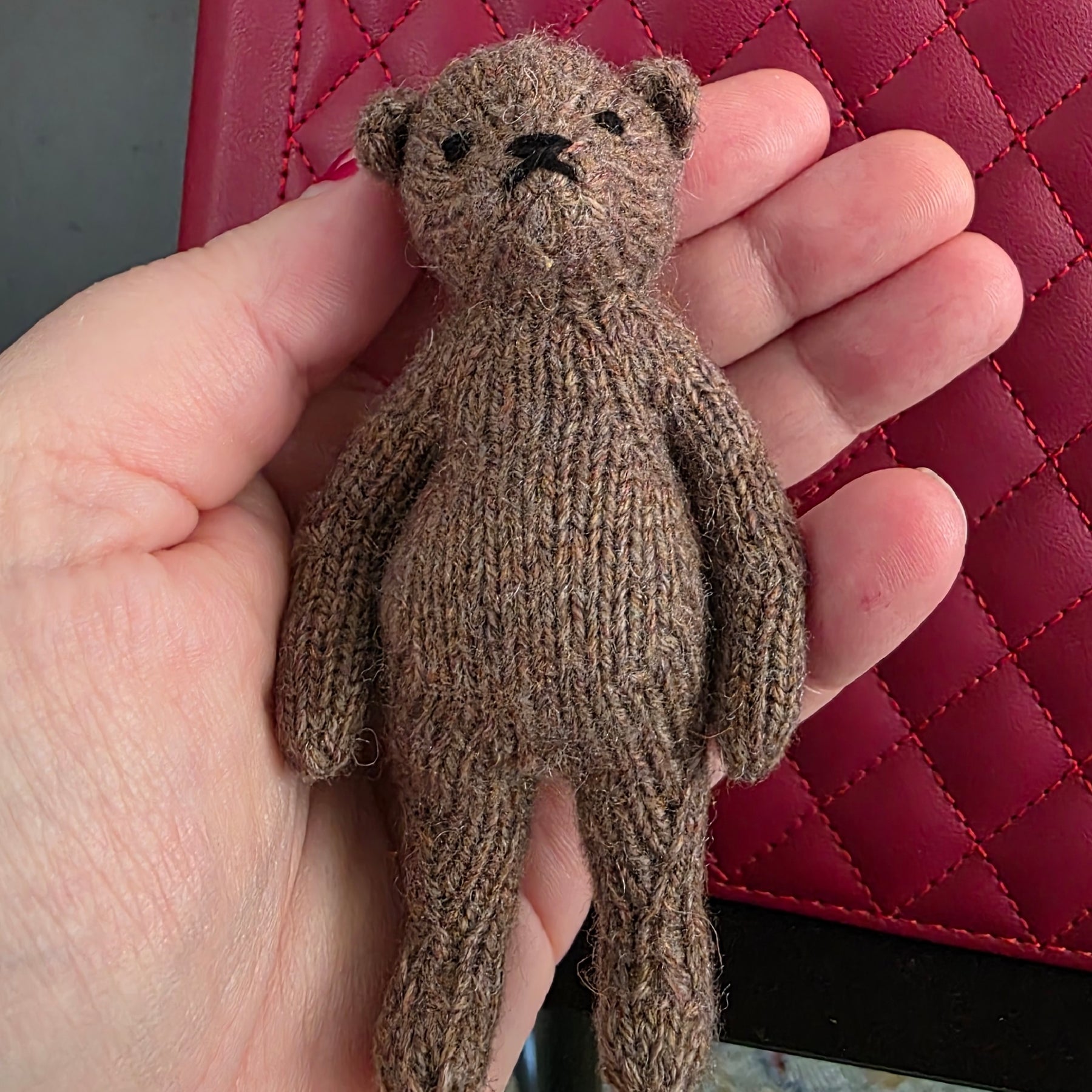 Small hand knitted bear with removeable clothes