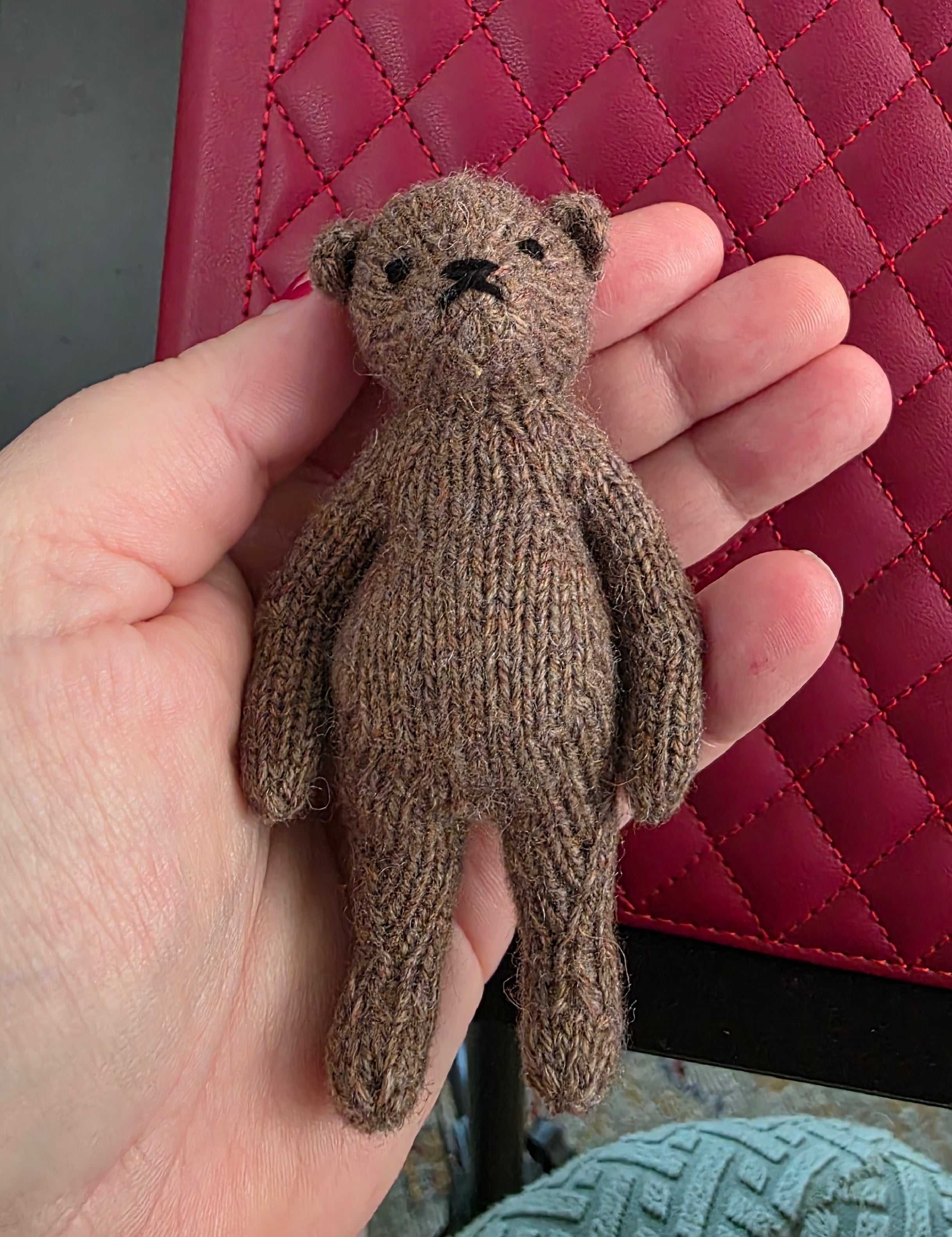 Small hand knitted bear with removeable clothes
