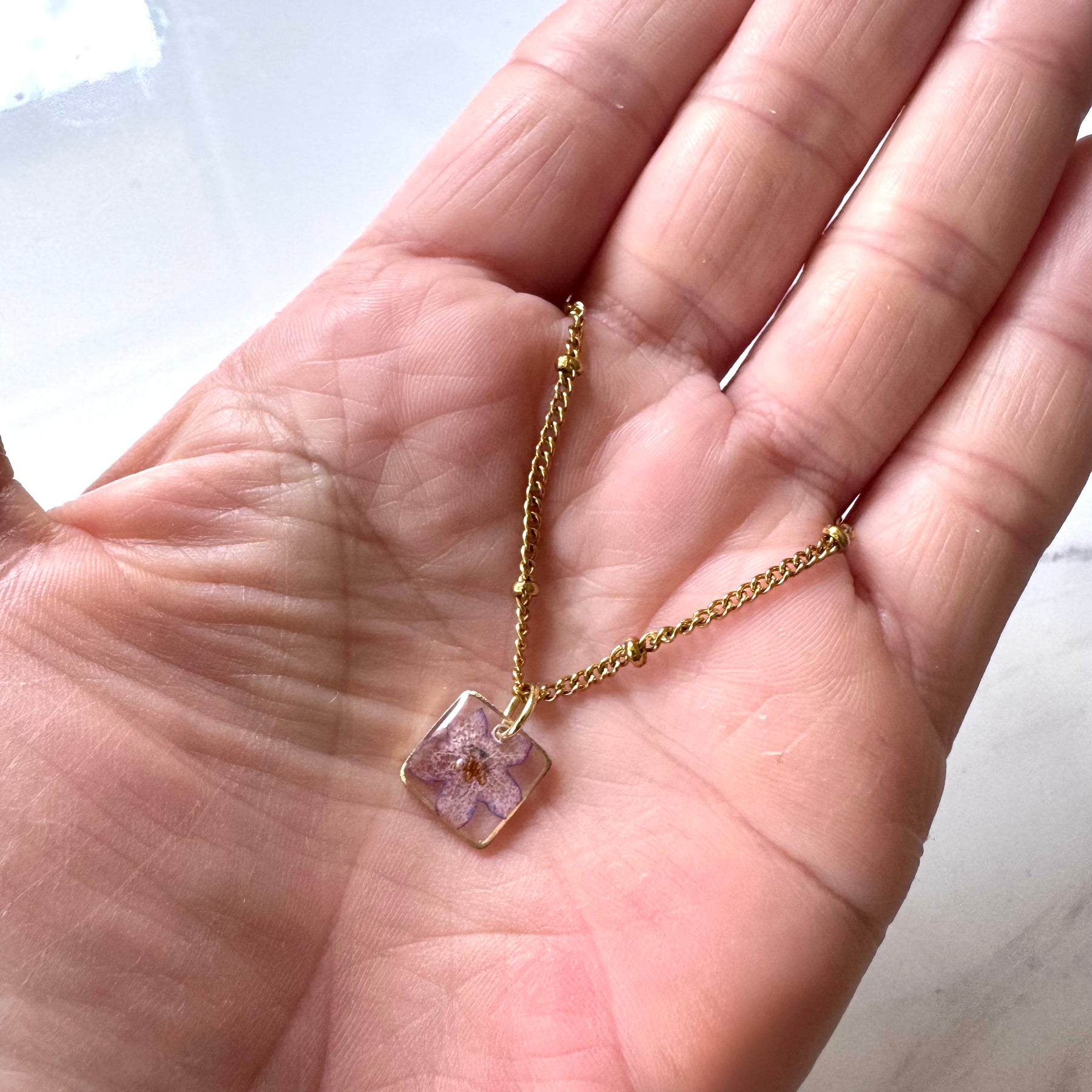 Gold plated resin necklace with purple wildflower