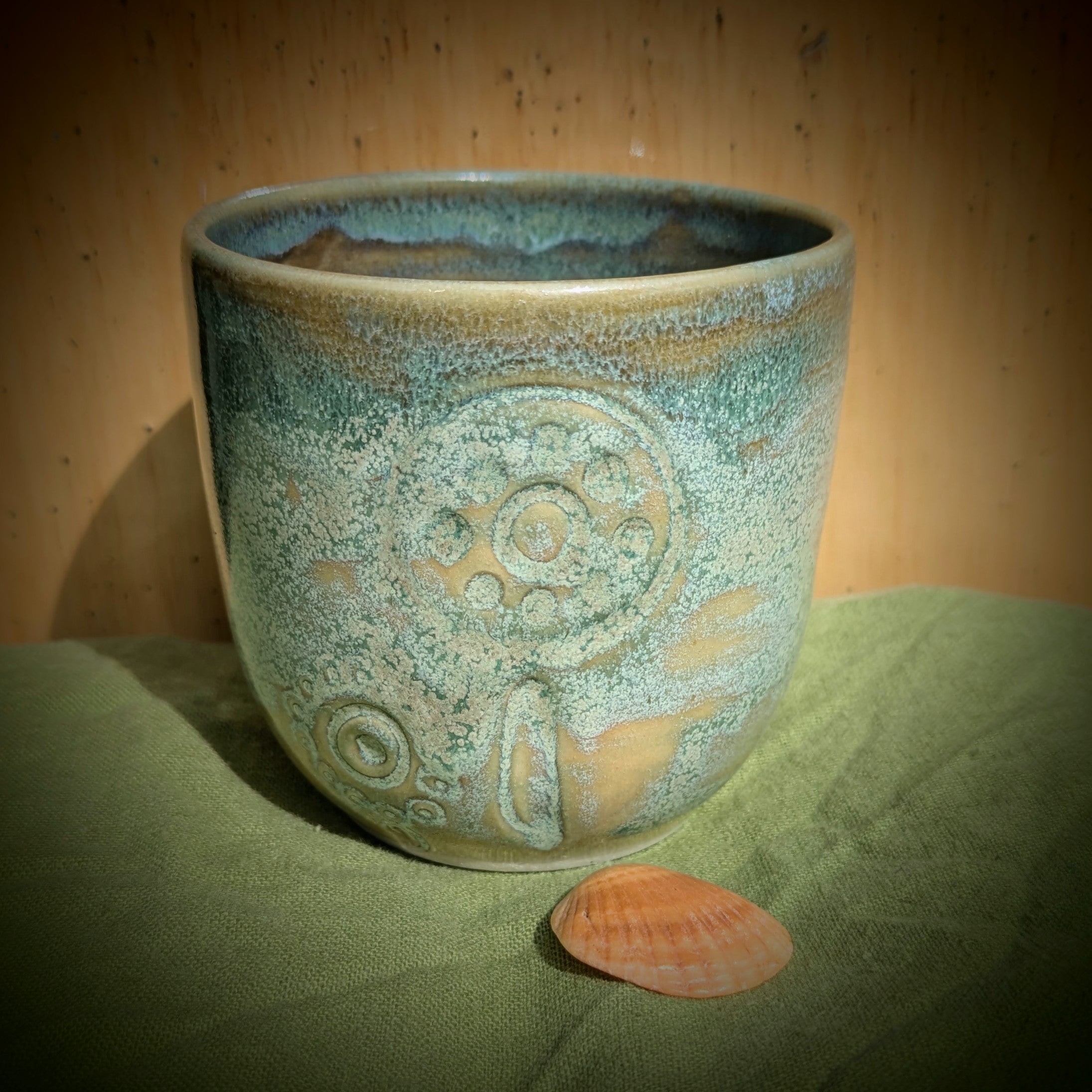 Cup in soft, mottled mossy greens and warm sandy colour