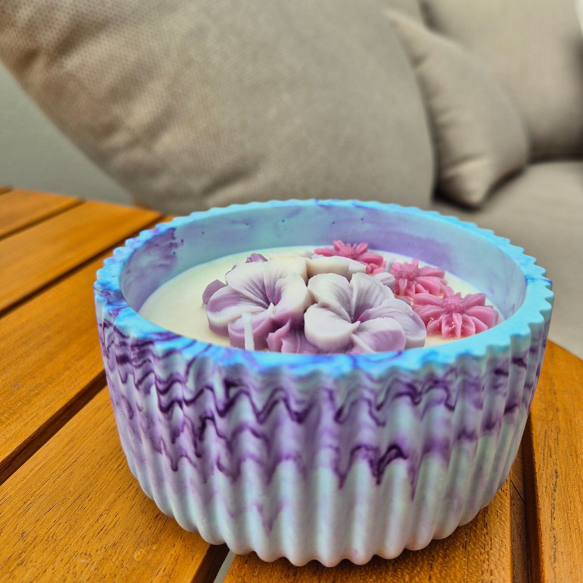 Round blue and purple concrete bowl candle with frangipani flower