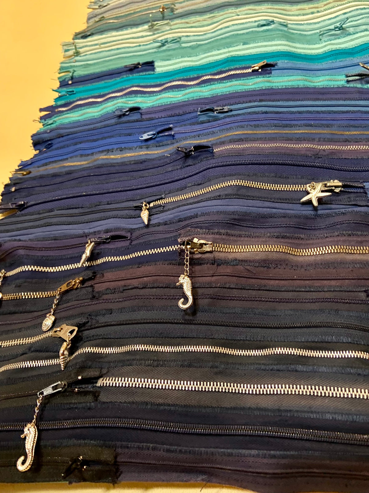 Upcycled 90 zips textile wall hanging. Ocean & Sky theme. Adorned with charms. Blue colour scheme. Ready to hang includes 2 x dowel rods