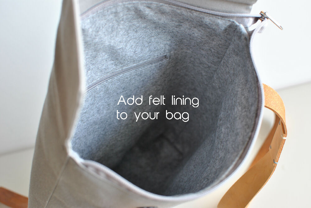 "Add fet lining to your bag" The inside of a grey canvas backpack with grey felt lining and an inside zipper pocket. The bag has leagther straps.