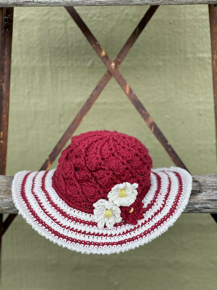 Cherry red spiral sun hat with daisy trim.