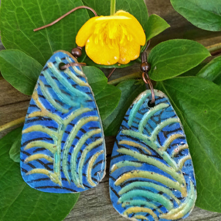 Hand made earrings with painted and carved details. Blue, green, yellow, black