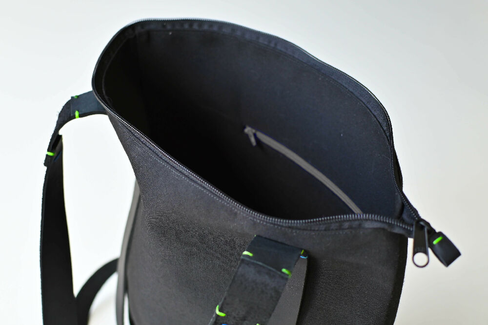 The inside of a black zipper canvas daypack with an internal zipper pocket.