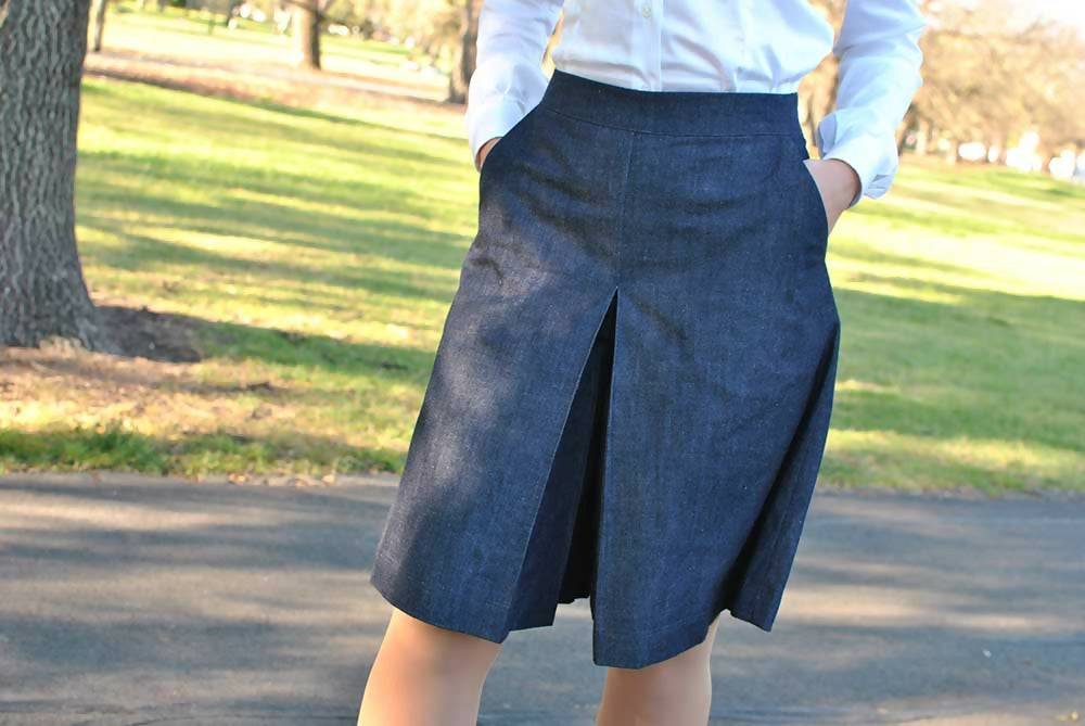 A denim coulotte skirt worn by a woman who holds her hands in her pockets.