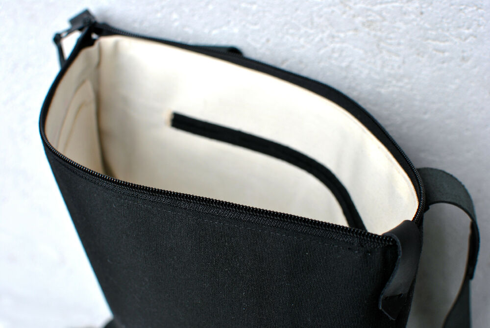 the white inside with black internal pocket of a black backpack with zipper.