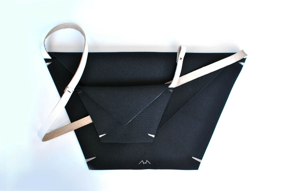 back minimalist envelope bag with matching detechable matching pochette, made from canvas and off-white colour leather strap lying on a white surface.