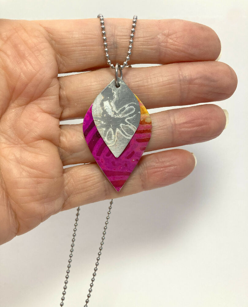 Printed and dyed anodised aluminium with textured flower motif pendant