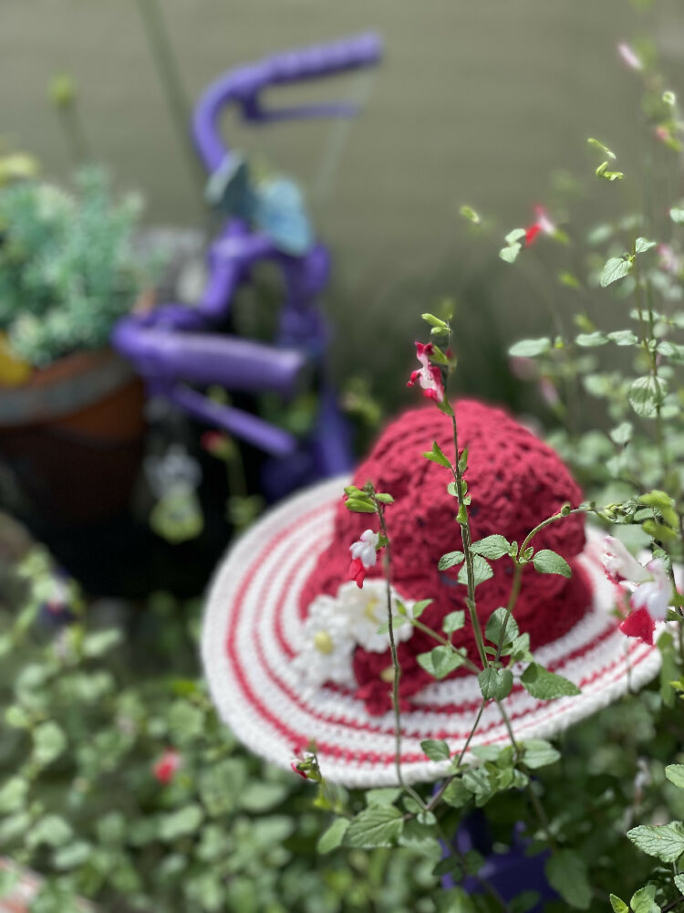 Cherry red spiral sun hat with daisy trim.
