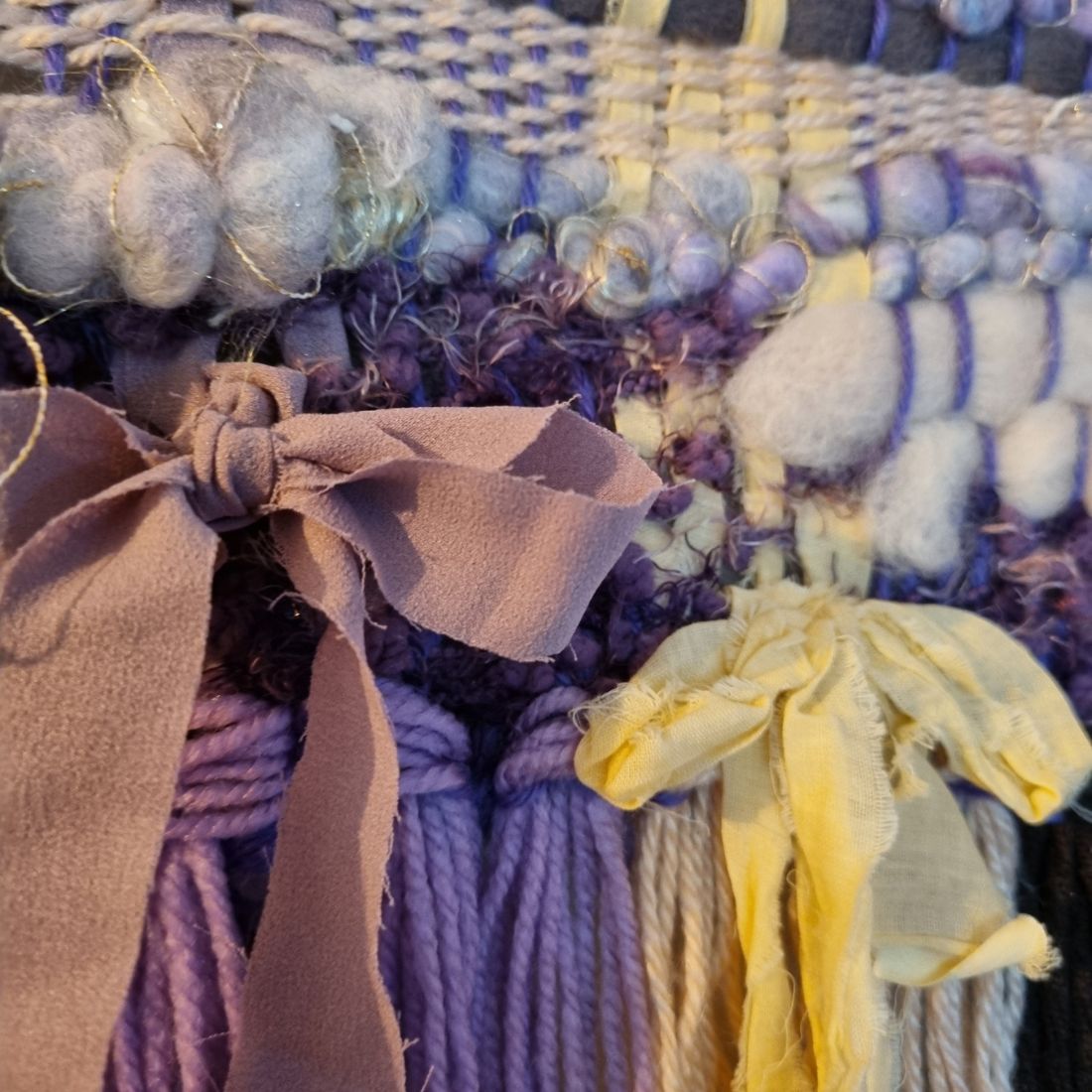 Handwoven textured wall hanging in purple, yellow and brown