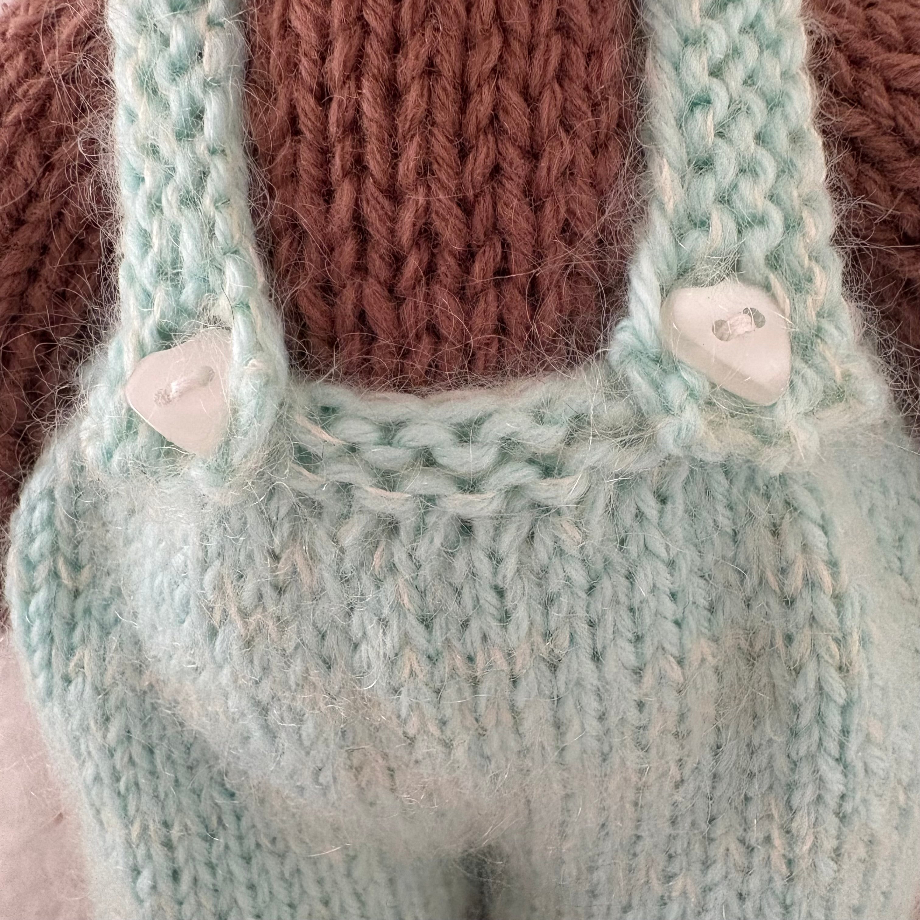 Little knitted bear in overalls, hat and scarf
