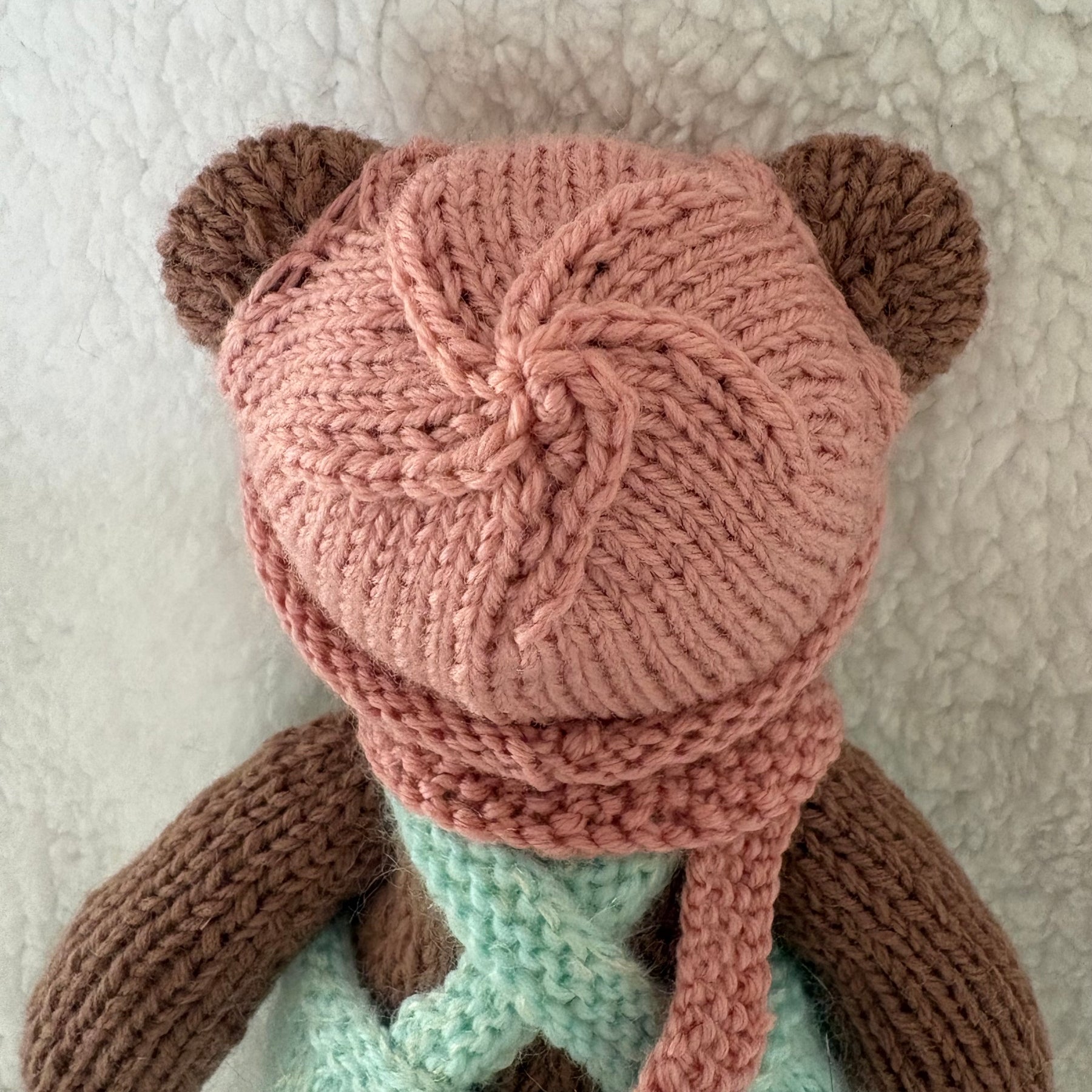 Little knitted bear in overalls, hat and scarf