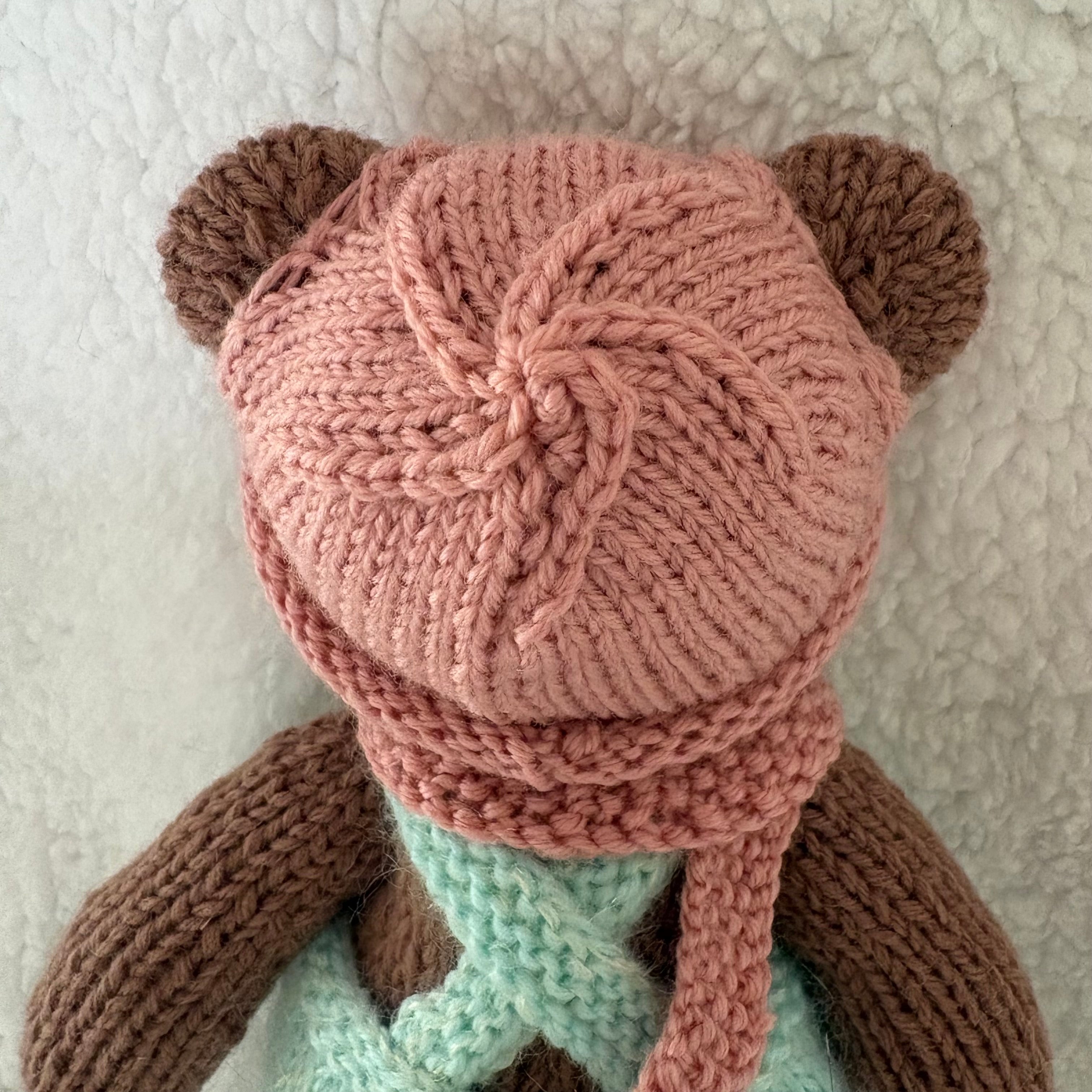 Little knitted bear in overalls, hat and scarf