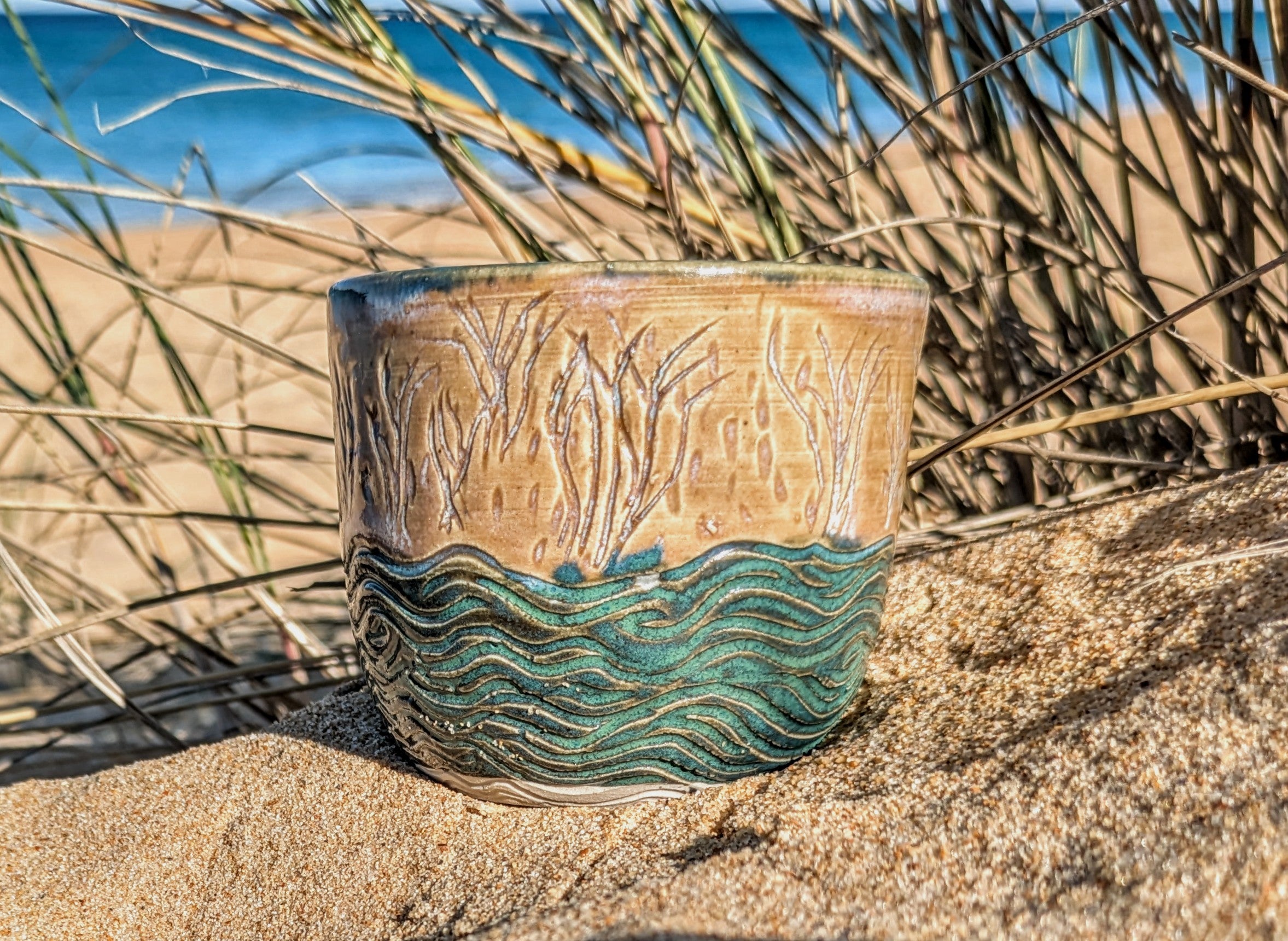 Sand dunes reeds and water tumbler