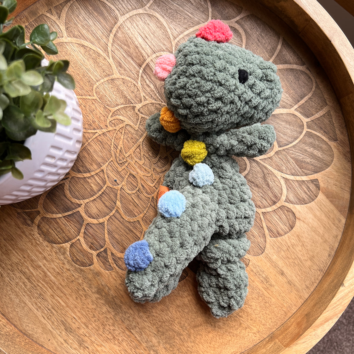 Handmade crochet Mini Dinosaur modern lovey with knotted legs and rainbow spikes.