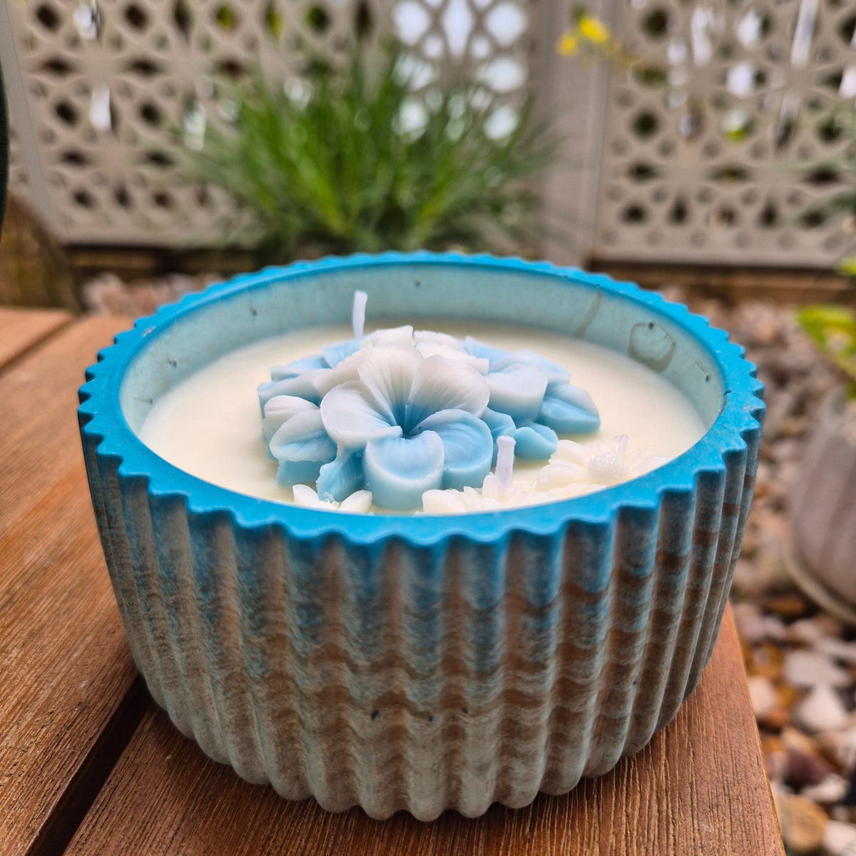 Round blue and gold concrete bowl candle with frangipani flower
