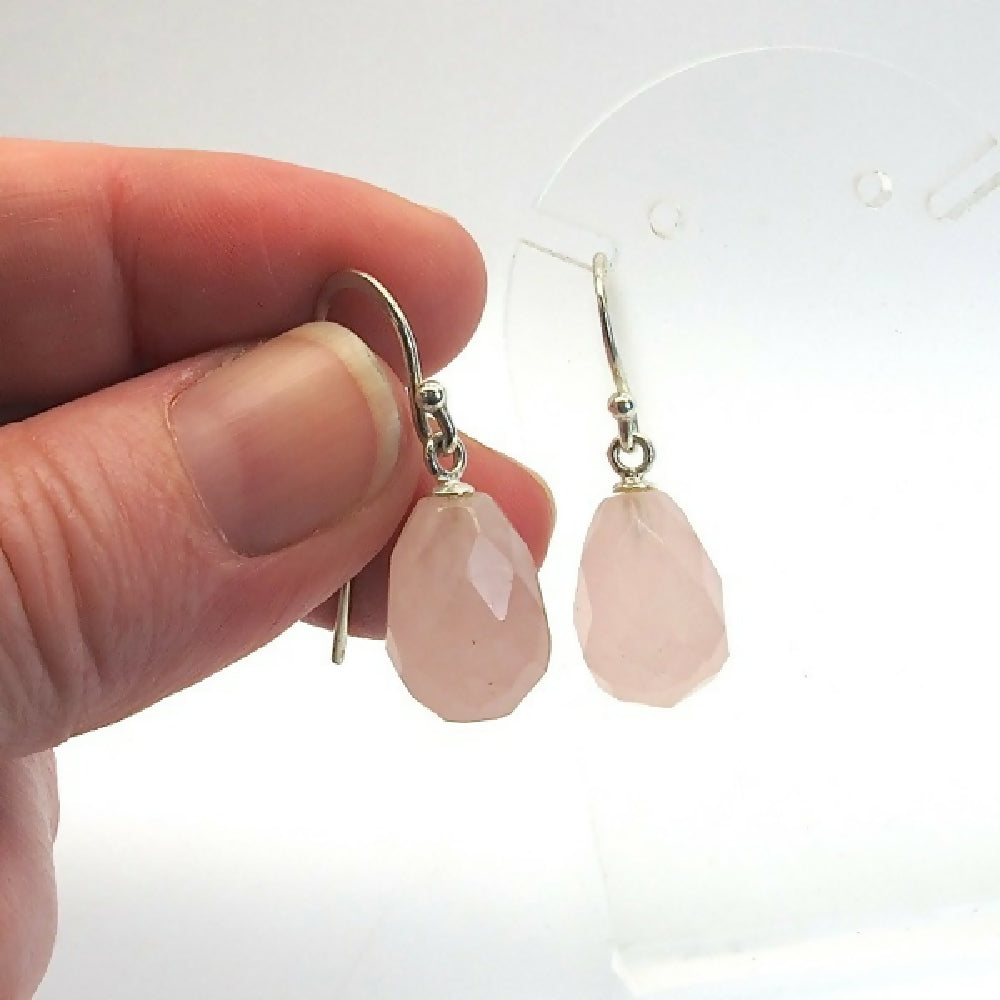 Rose - quartz - briolettes - sterling - silver - held - by - hand - white - background