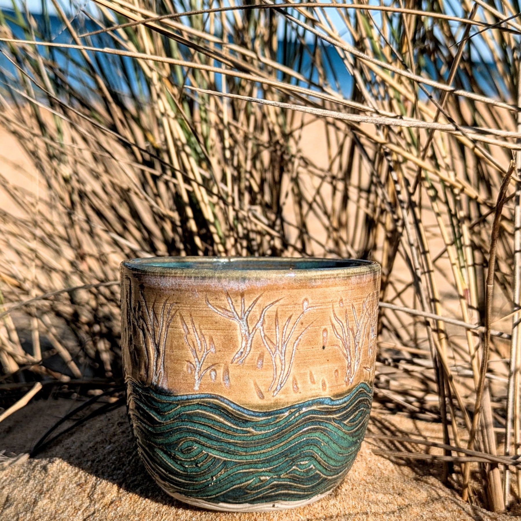 Sand dunes reeds and water tumbler