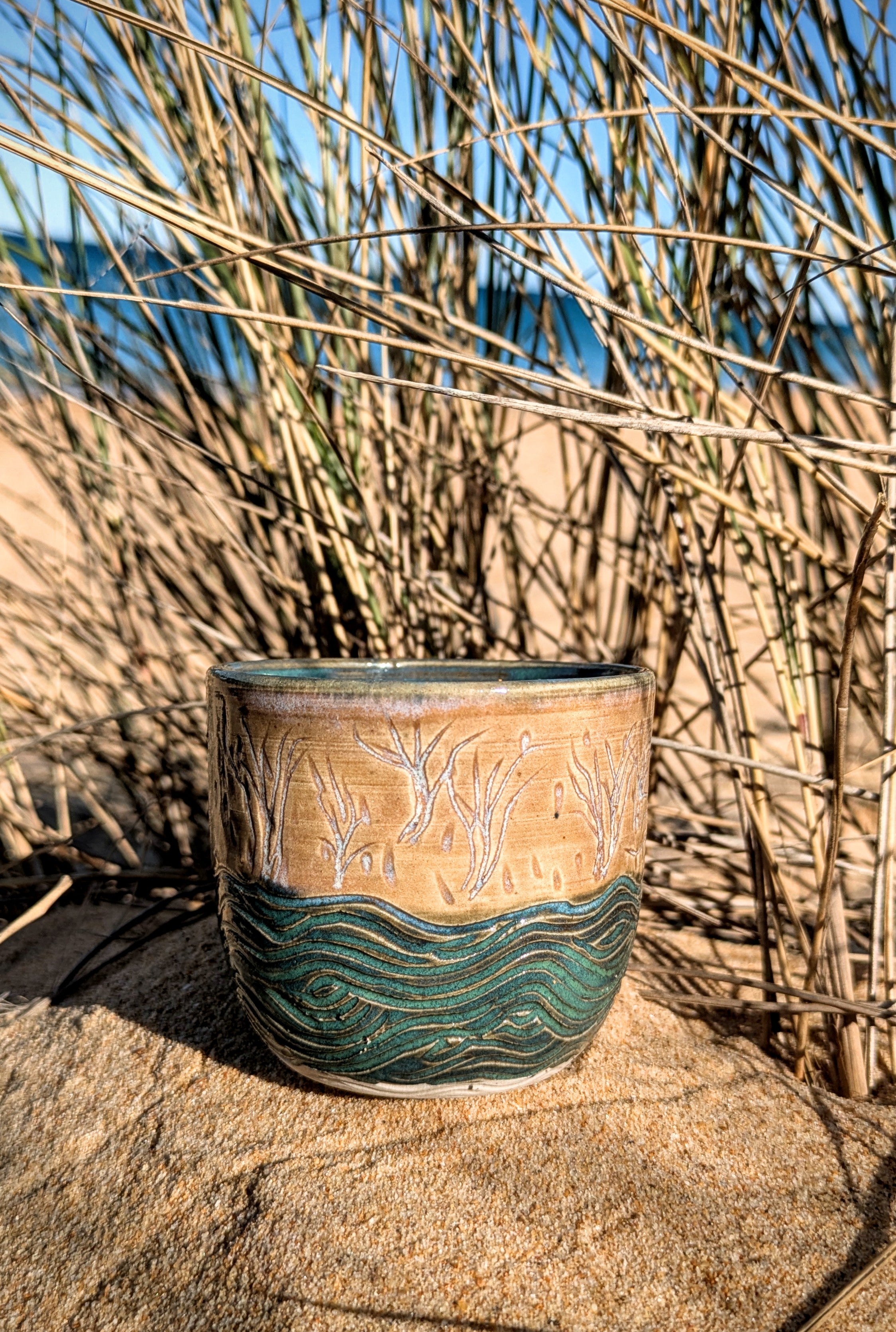 Sand dunes reeds and water tumbler