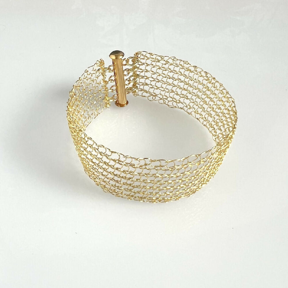 Knitted gold colour bracelet on white