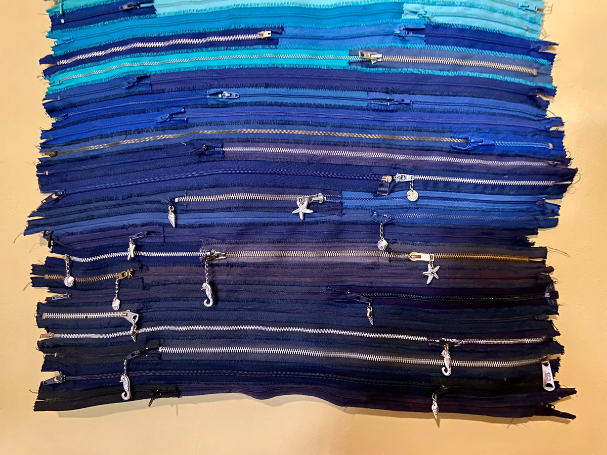 Upcycled 90 zips textile wall hanging. Ocean & Sky theme. Adorned with charms. Blue colour scheme. Ready to hang includes 2 x dowel rods