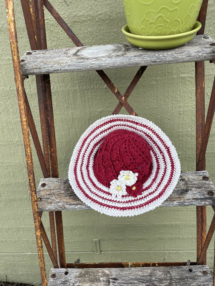 Cherry red spiral sun hat with daisy trim.