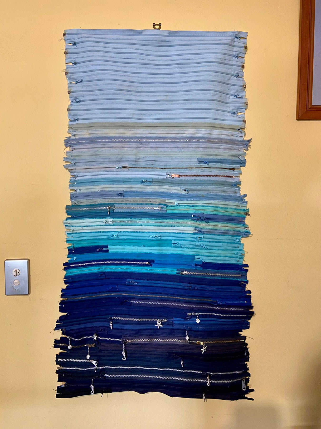 Upcycled 90 zips textile wall hanging. Ocean & Sky theme. Adorned with charms. Blue colour scheme. Ready to hang includes 2 x dowel rods