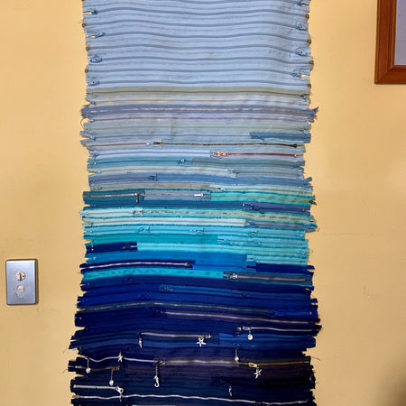 Upcycled 90 zips textile wall hanging. Ocean & Sky theme. Adorned with charms. Blue colour scheme. Ready to hang includes 2 x dowel rods