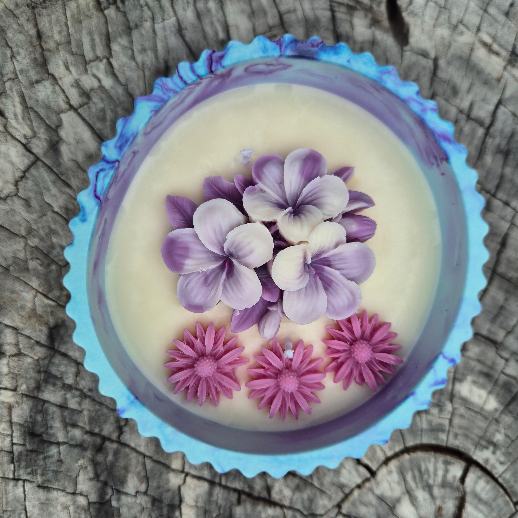 Round blue and purple concrete bowl candle with frangipani flower