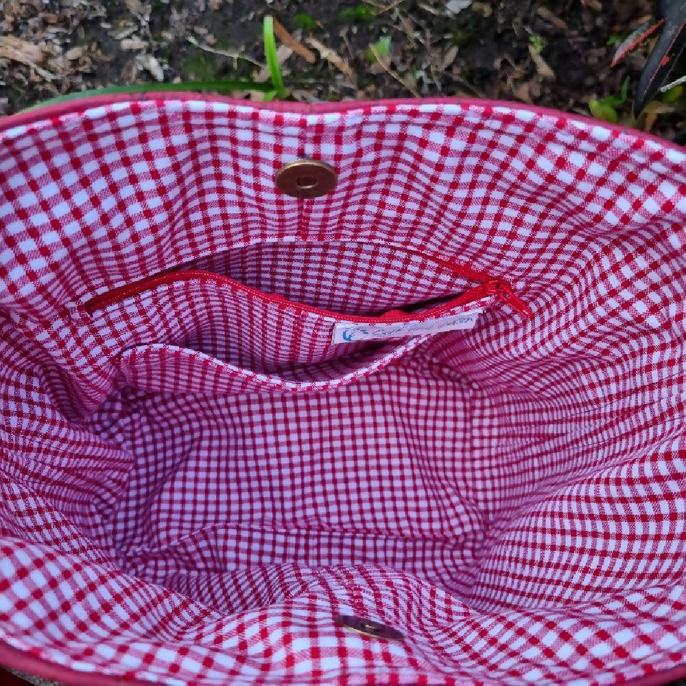 Interior view showing a zipped pocket with a slip pocket underneath. The lining fabric is a deep red check.