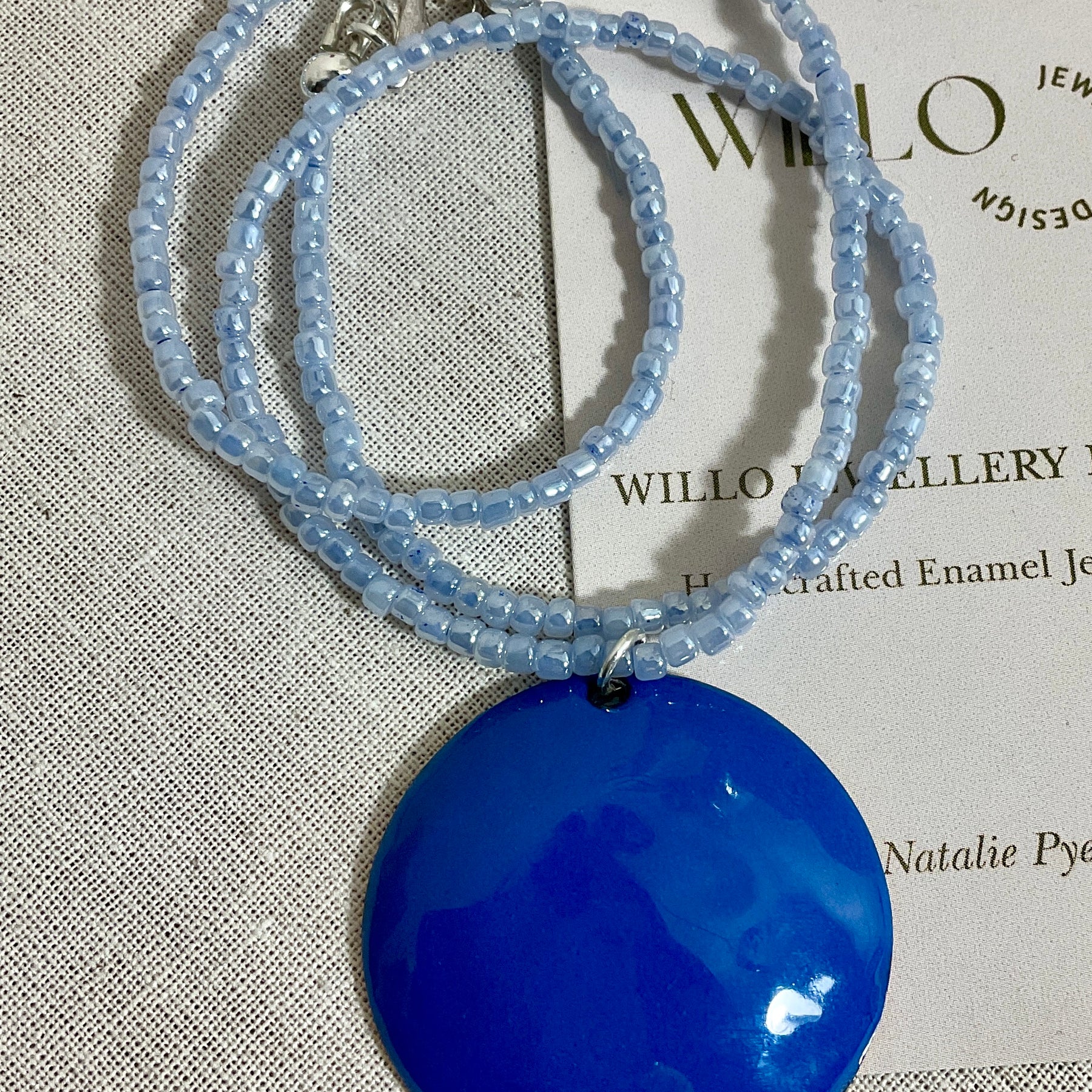 Blue enamel pendant on glass seed bead necklace.