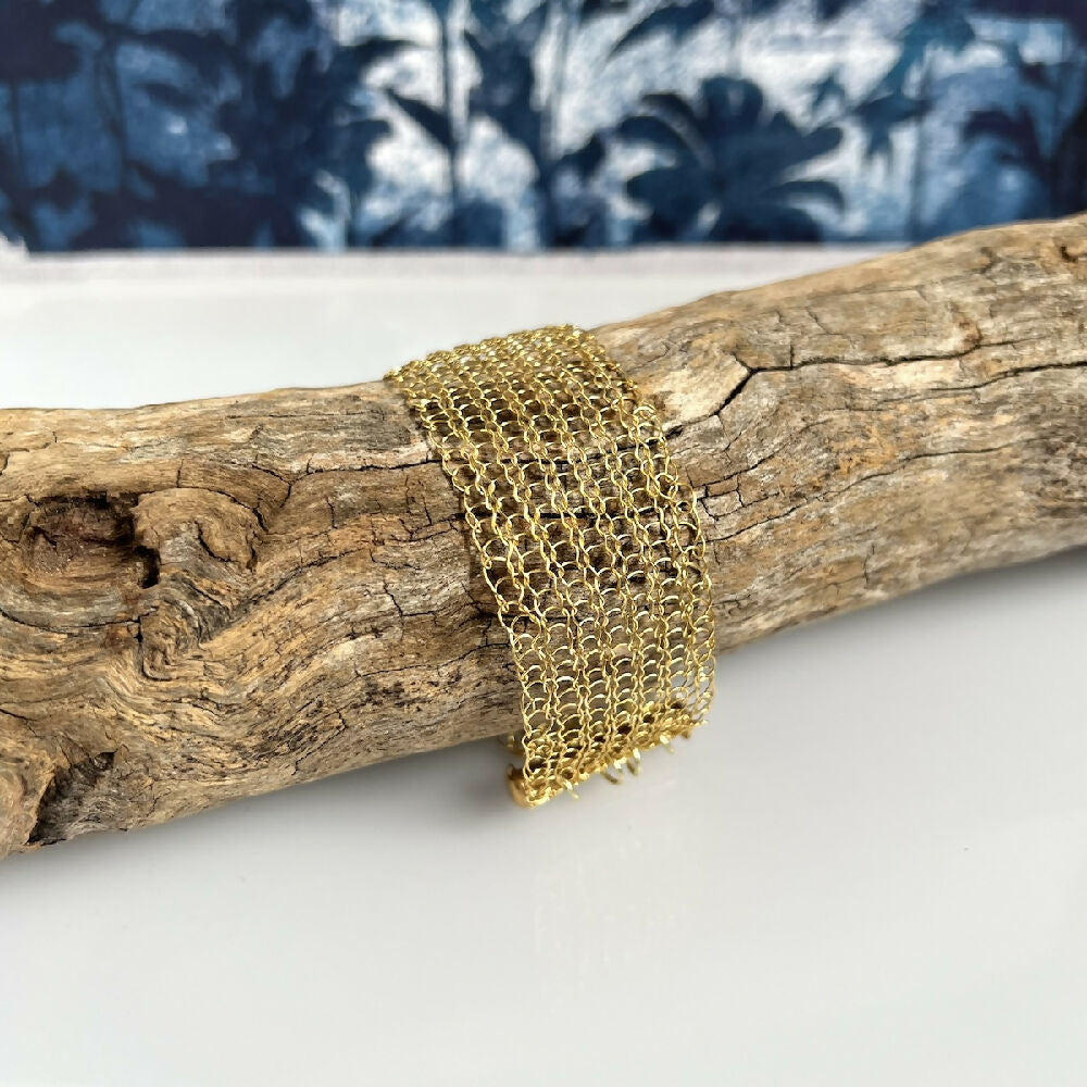 Knitted gold colour bracelet on log