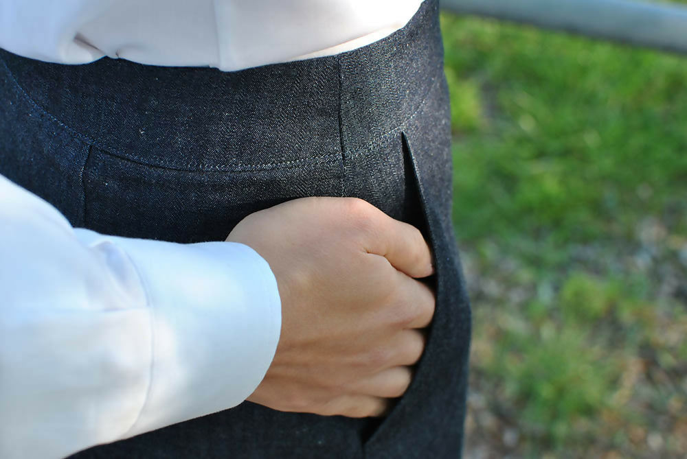 Details of adenim skirt. A woman is wearing them with white shirt while holding her hands in the pockets.