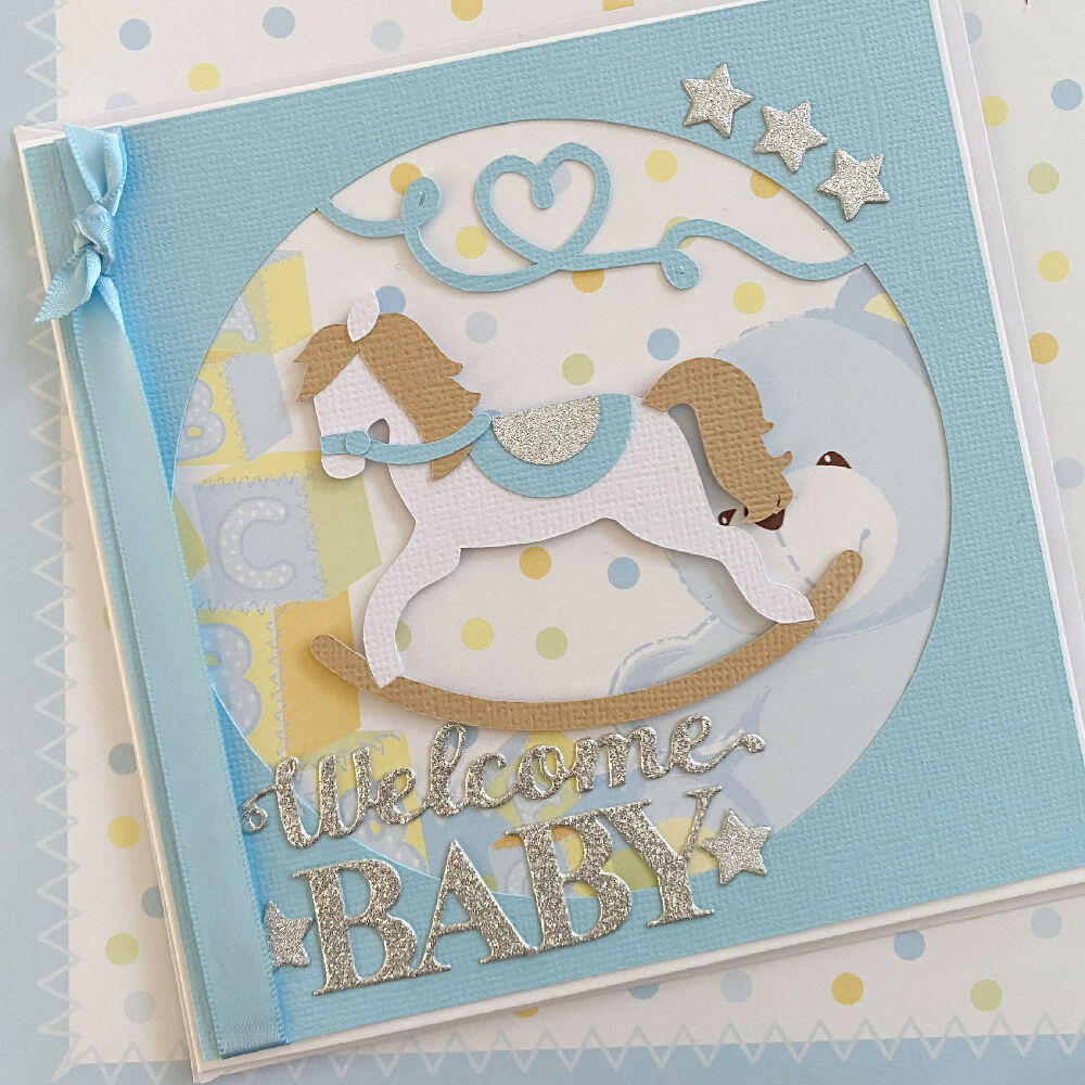 Rocking horse, new baby boy card. Welcome baby in blue.