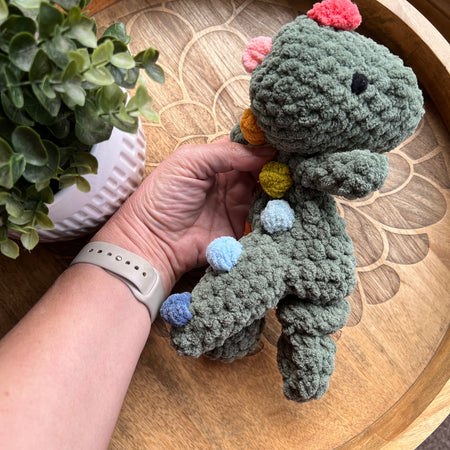 Handmade crochet Mini Dinosaur modern lovey with knotted legs and rainbow spikes.