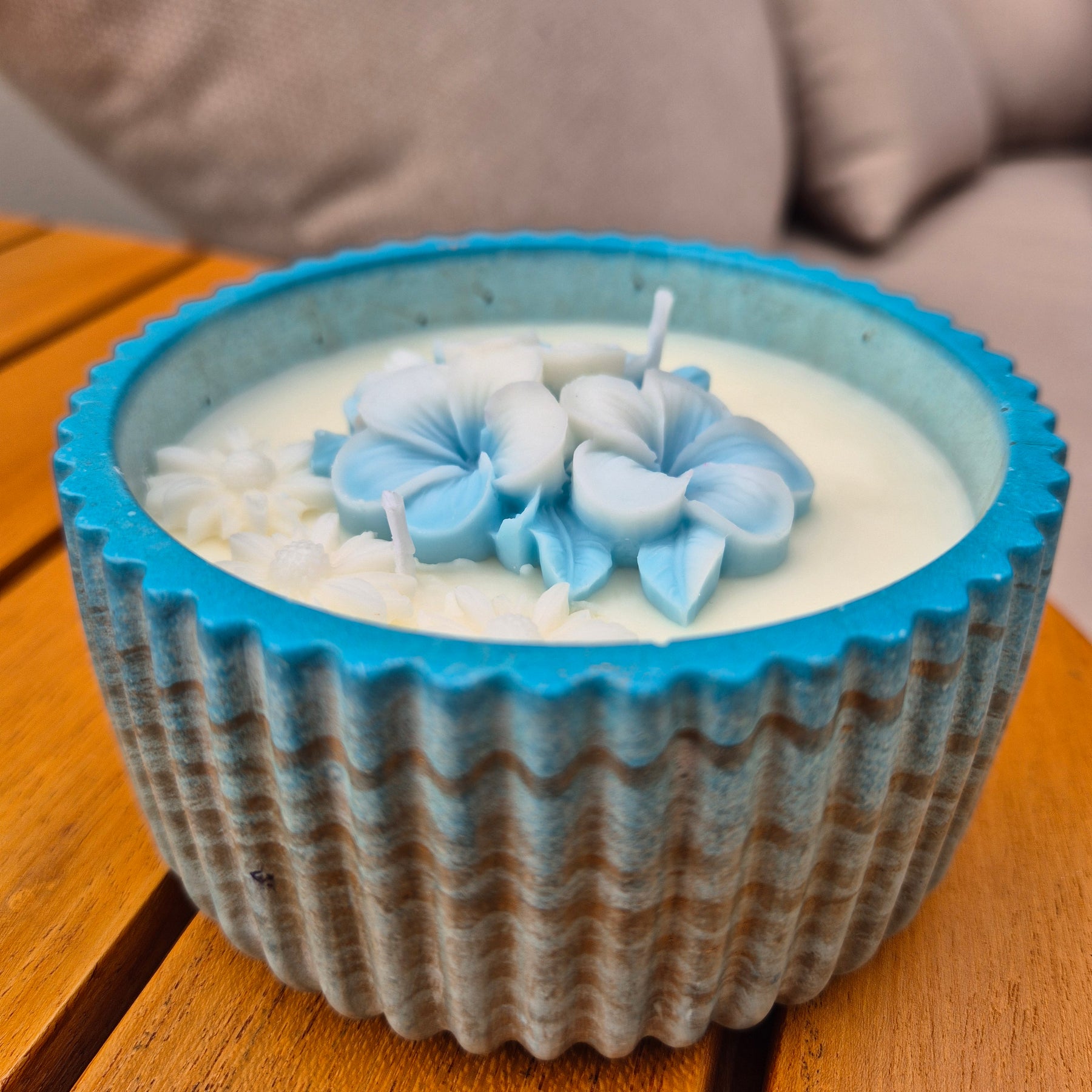 Round blue and gold concrete bowl candle with frangipani flower