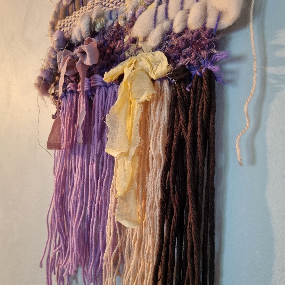 Handwoven textured wall hanging in purple, yellow and brown