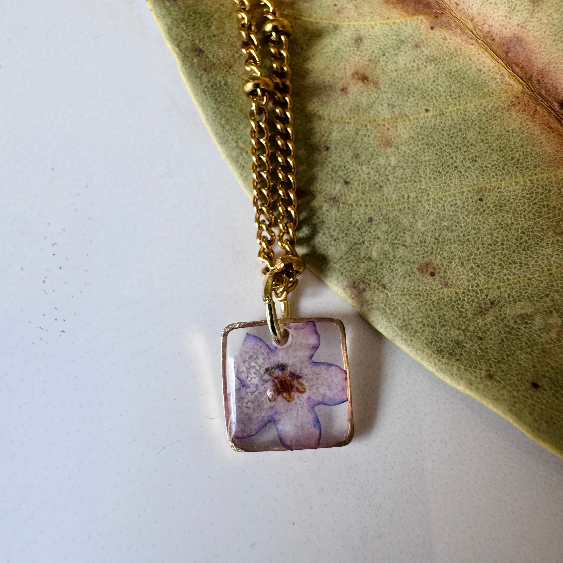 Gold plated resin necklace with purple wildflower