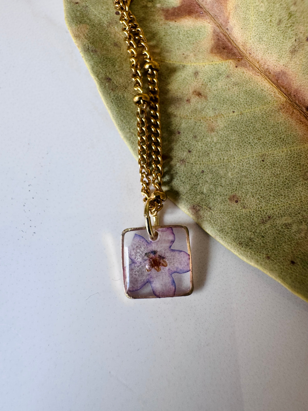 Gold plated resin necklace with purple wildflower