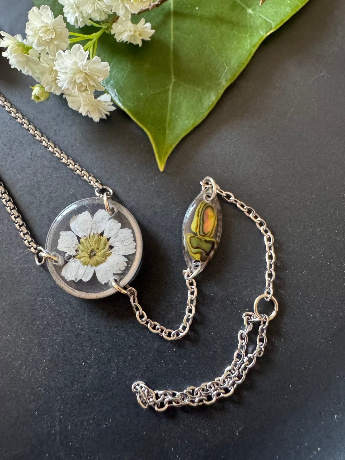 Botanical resin hand chain in silver with pressed flowers and cowrie shell