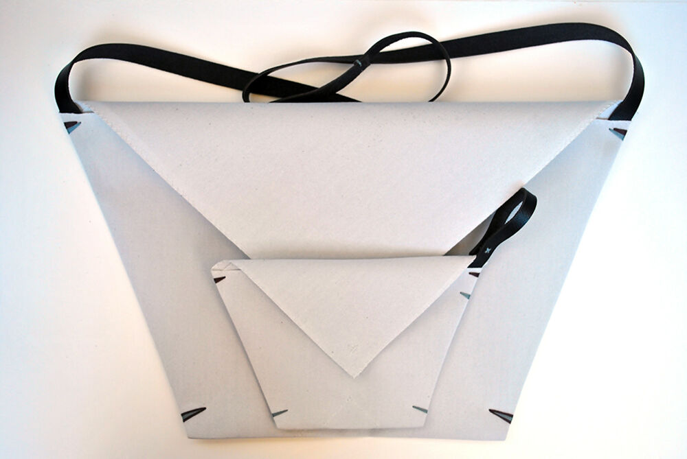 light Gray minimalist envelope bag with matching detechable matching pochette, made from canvas and black leather strap are lying on a white surface.