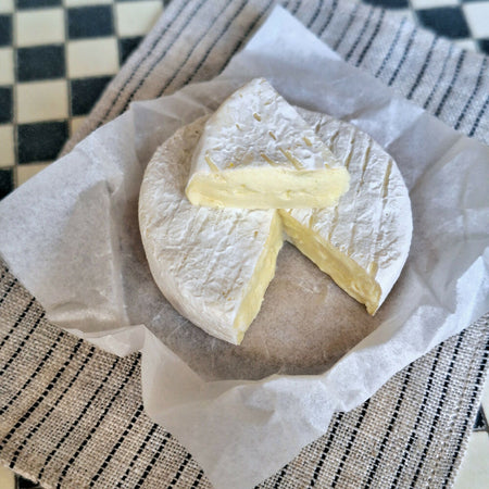 LARGE BRIE cheese with a cut wedge