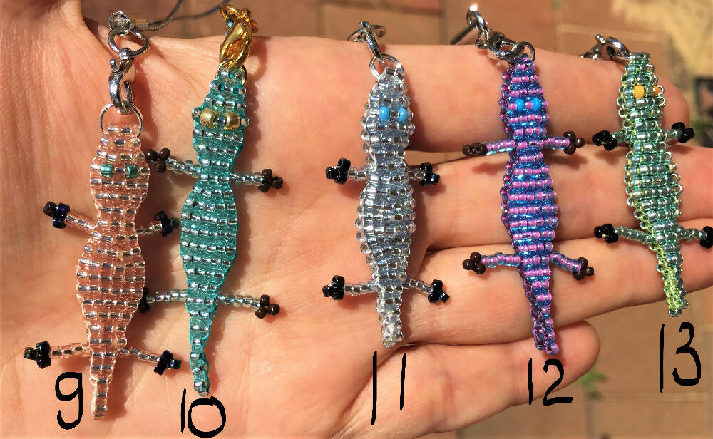 On the palm there are 5 Naryanabeads beaded croc with numbers.Number 9 next to shiny pale peach, number 10 next to shiny ligh blue, number 11 next to shiny pale blue, number 12 next to shiny light purple, number 13 next to metallic mint one