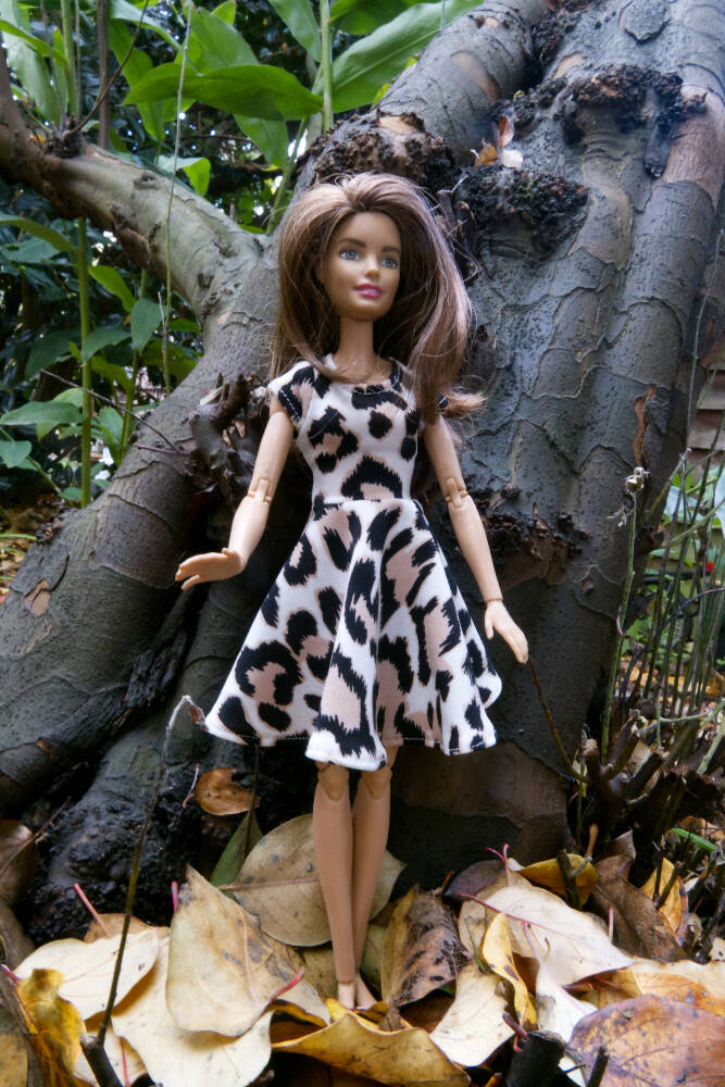 Photo of barbie in leopard print dress standing in front of a tree