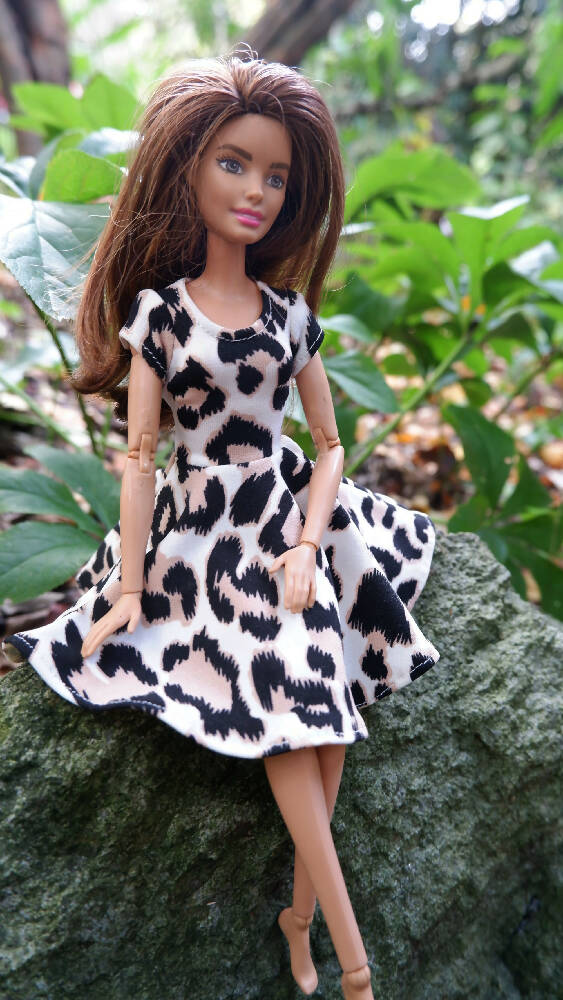Photo of barbie in leopard print dress sitting on a rock